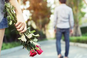 Mujer con rosas en la mano, mientras un hombre se aleja de ella en el parque. (Getty Images)