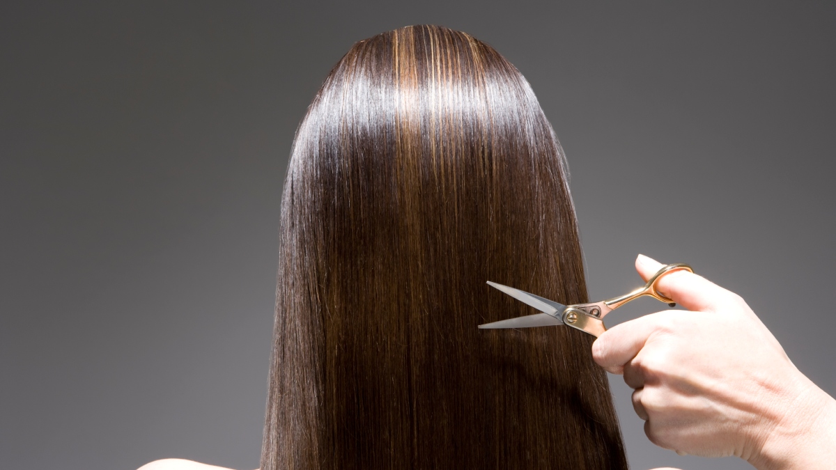 Mujer con tijeras cortando su cabello para que crezca rápido / Foto: GettyImages