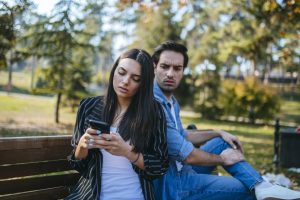 Mujer revisando el celular de su pareja, mientra él la mira (Getty Images)