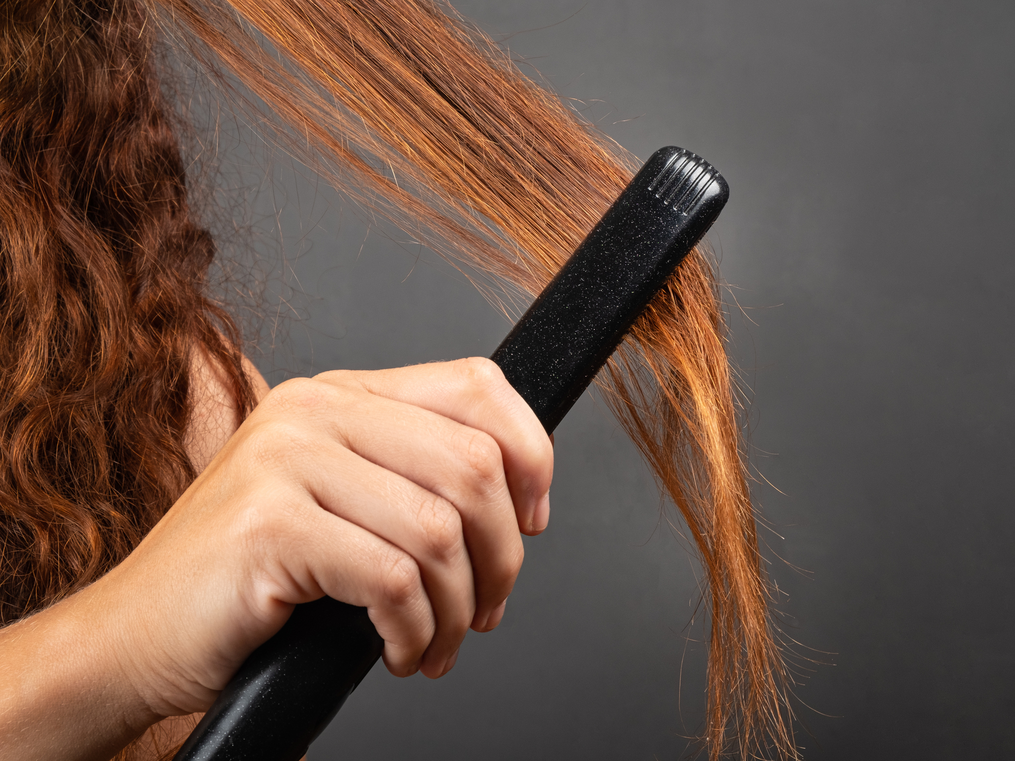 Mujer planchando un mechón de su cabello (Getty Images)