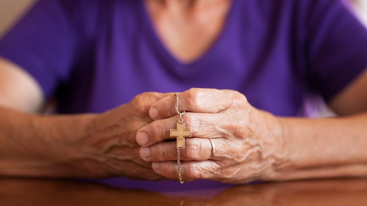 Mujer orando con una camándula o corona del rosario / Foto: GettyImages