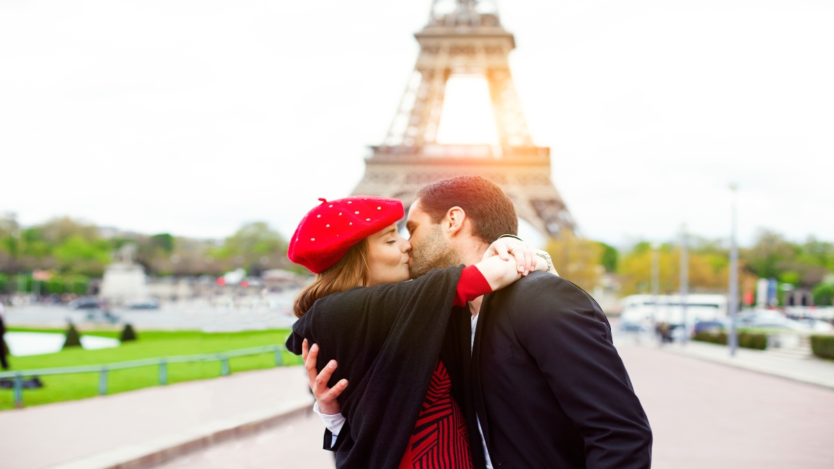 Pareja besánsose frente a la torre Eiffel (Foto vía Getty Images)