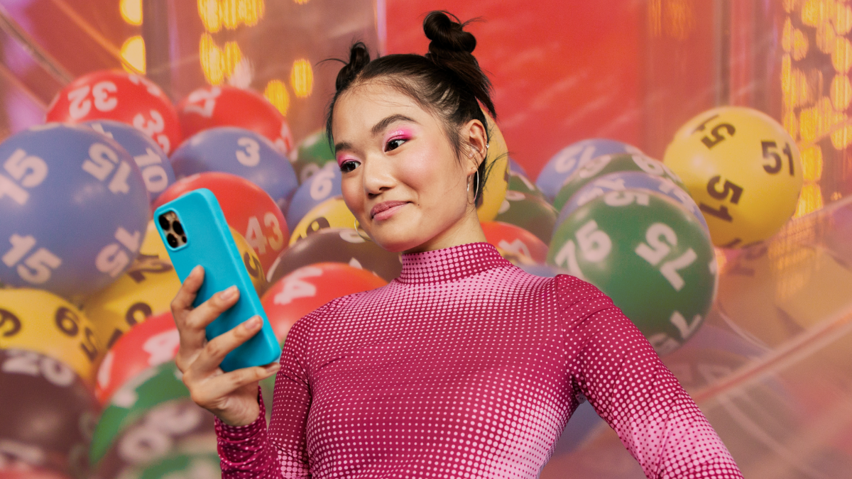 Persona mirando su celular con números de la suerte de fondo. Crédito: Getty images.