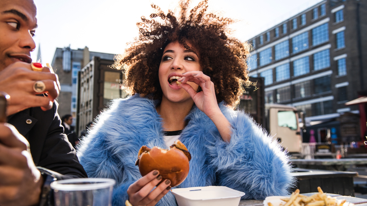 Personas comiendo hamburguesa. Crédito:Getty images.