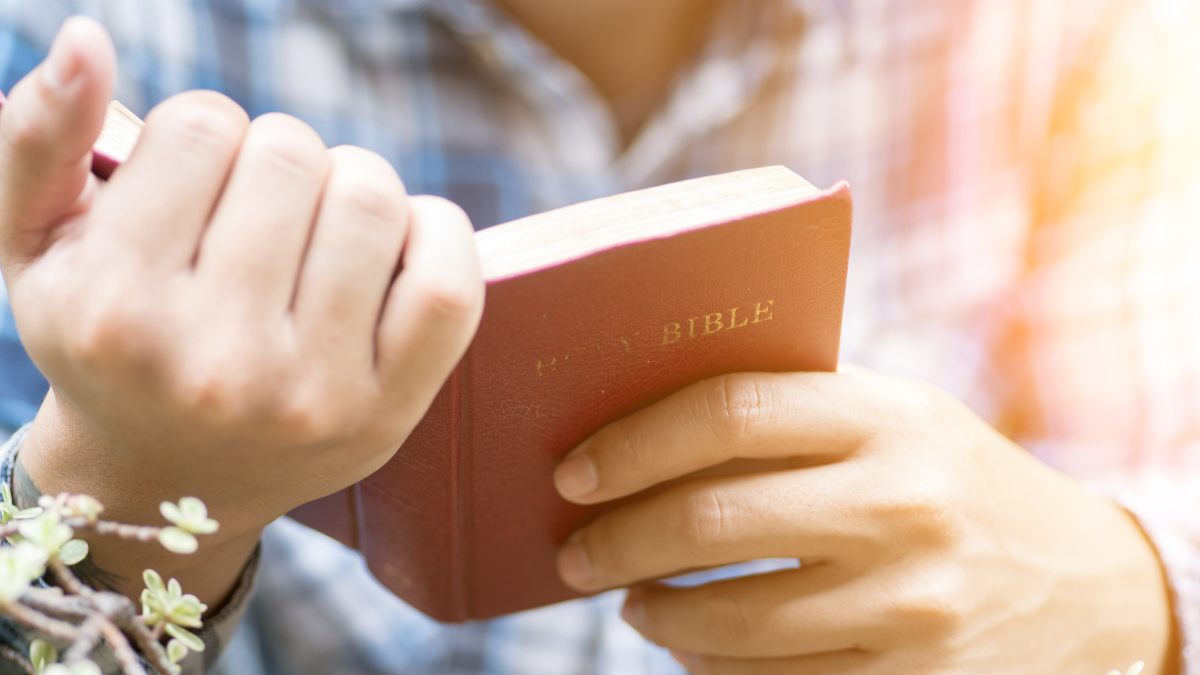 Persona orando con la biblia en la mano. | Crédito: Getty images.